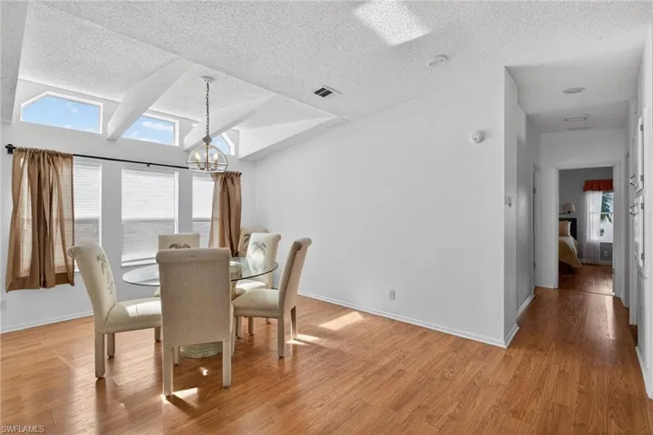 Dining area featuring light wood-type flooring, vaulted ceiling, and a textured ceiling