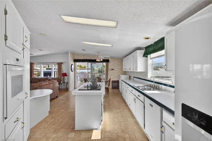 Kitchen featuring white cabinets, white appliances, open floor plan, a textured ceiling, and a center island