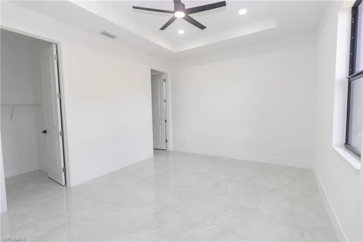 Bedroom featuring a spacious closet, a ceiling fan, recessed lighting, and a raised ceiling