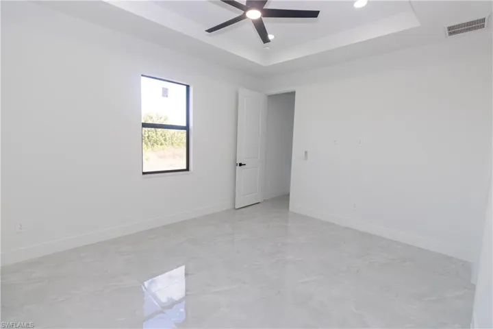 Bedroom with a raised ceiling and ceiling fan