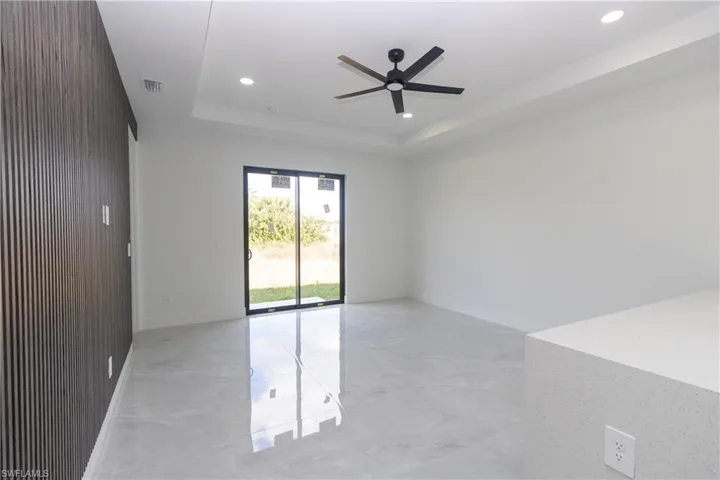 Living room featuring ceiling fan, a tray ceiling, recessed lighting, and light marble finish flooring