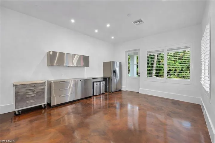 Kitchen featuring finished concrete flooring, stainless steel refrigerator with ice dispenser, light countertops, recessed lighting, and modern cabinets