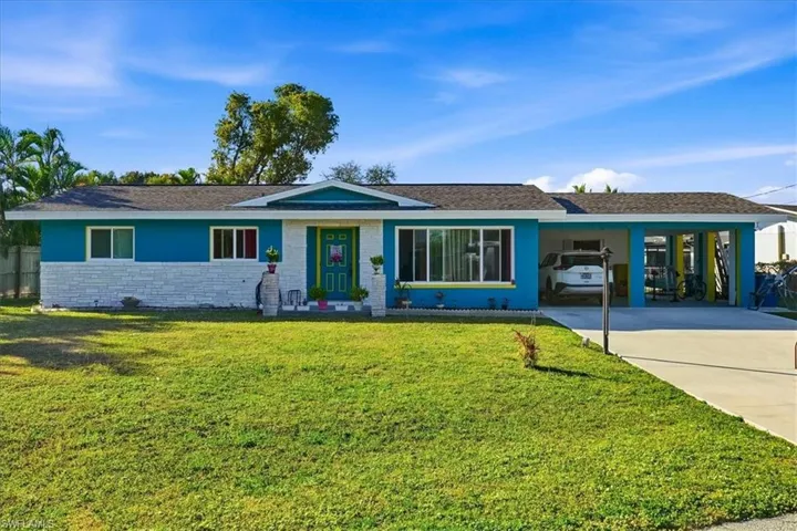 Ranch-style home featuring concrete driveway, a front lawn, an attached carport, stone siding, and a shingled roof