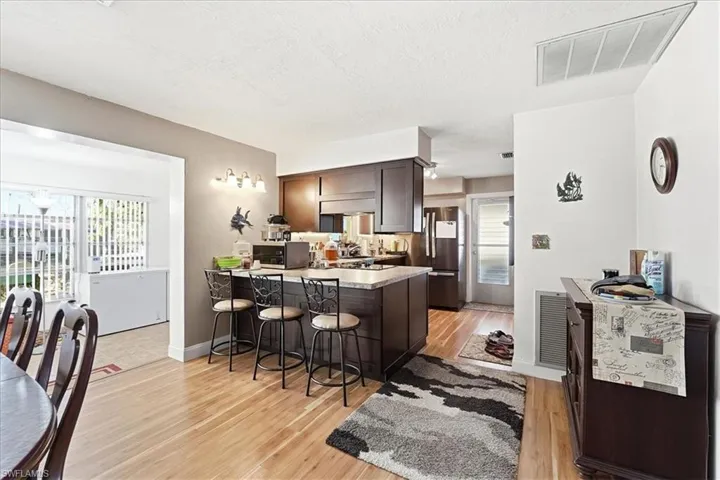 Kitchen with a kitchen breakfast bar, a peninsula, dark wood finish cabinetry, light countertops, and healthy amount of natural light