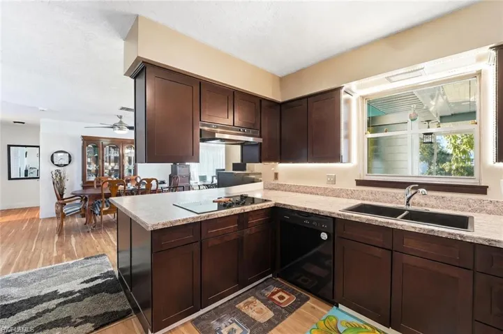 Kitchen featuring dark wood-finish cabinetry, light-toned countertops, and a double basin sink with a single-handle faucet