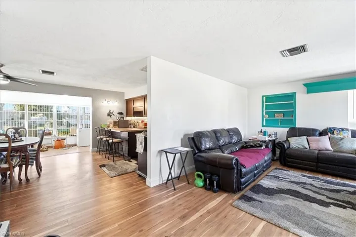 Living area featuring healthy amount of natural light, a ceiling fan, light wood-type flooring, and a textured ceiling
