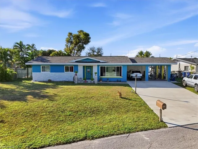 Ranch-style home with a carport, concrete driveway, roof with shingles, and stone siding