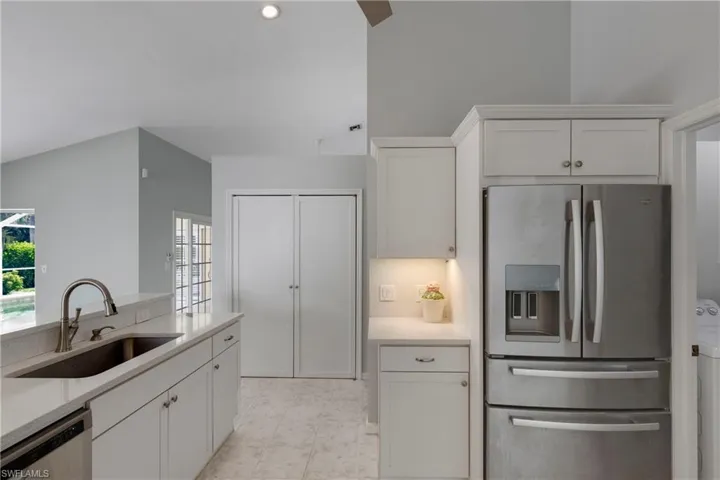 Kitchen featuring stainless steel appliances, a sink, white cabinetry, and washer / dryer