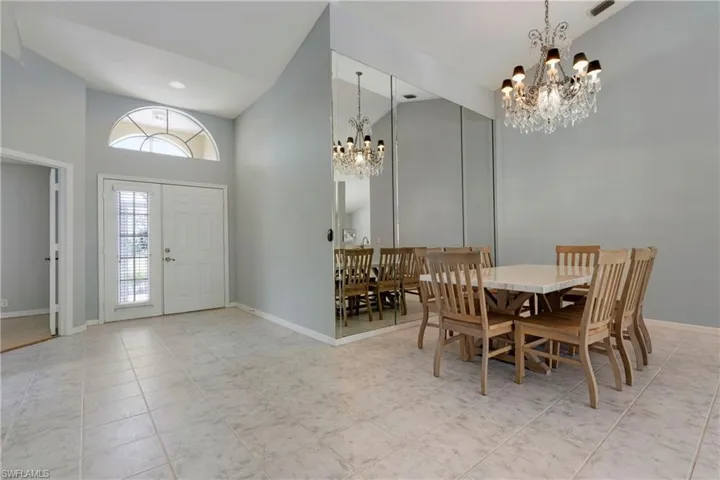 Dining area with a chandelier, high vaulted ceiling, baseboards, and light tile patterned flooring