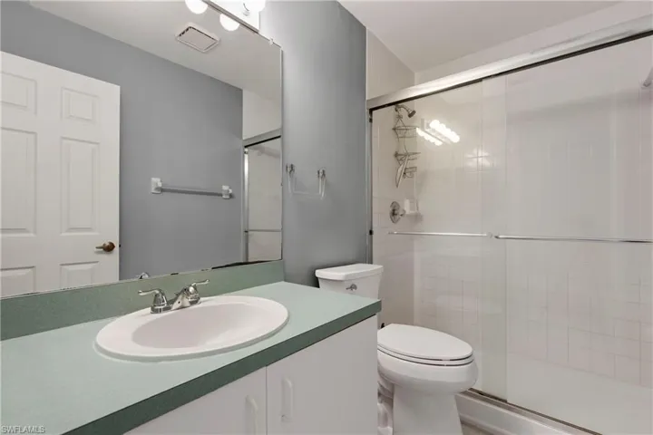 Bathroom featuring a tile shower, toilet, and vanity.
