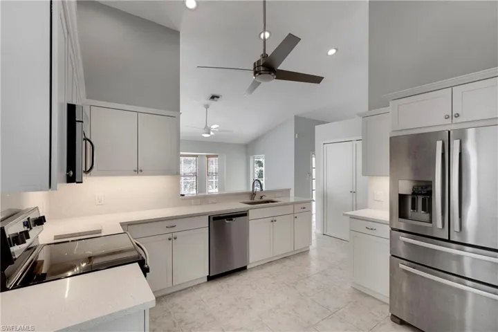 Kitchen featuring appliances with stainless steel finishes, high vaulted ceiling, a ceiling fan, a sink, and recessed lighting