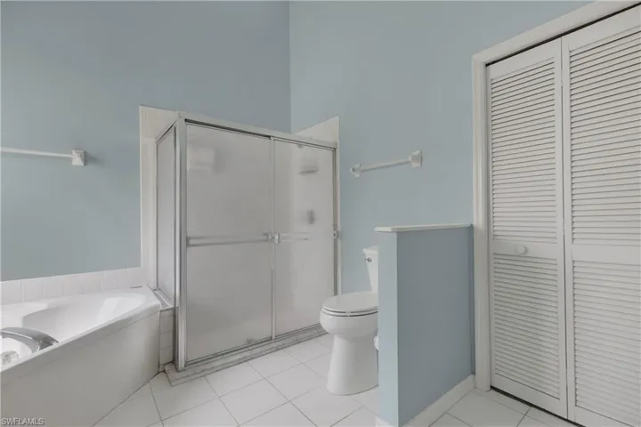 Full bath featuring a closet, toilet, a shower stall, and a garden tub