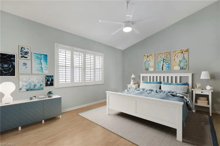 Bedroom featuring wood finished floors, vaulted ceiling, a ceiling fan, and plenty of natural lighting.