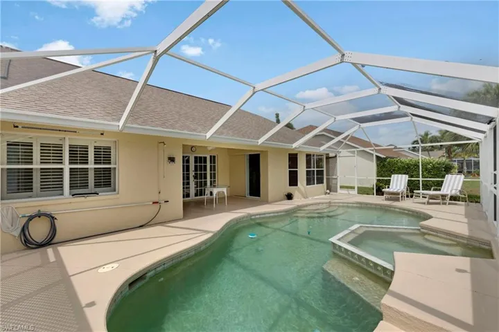 View of pool with a patio, a pool with connected hot tub, glass enclosure, and french doors.