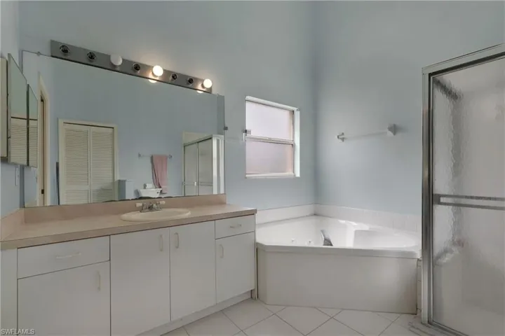 Bathroom with a stall shower, vanity, a tub with jets, tile patterned flooring, and a closet.