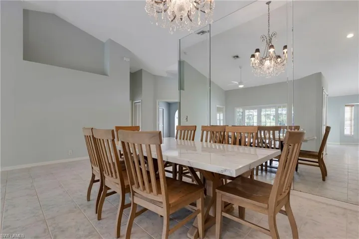 Dining area featuring a chandelier, high vaulted ceiling, baseboards, light tile patterned floors, and ceiling fan
