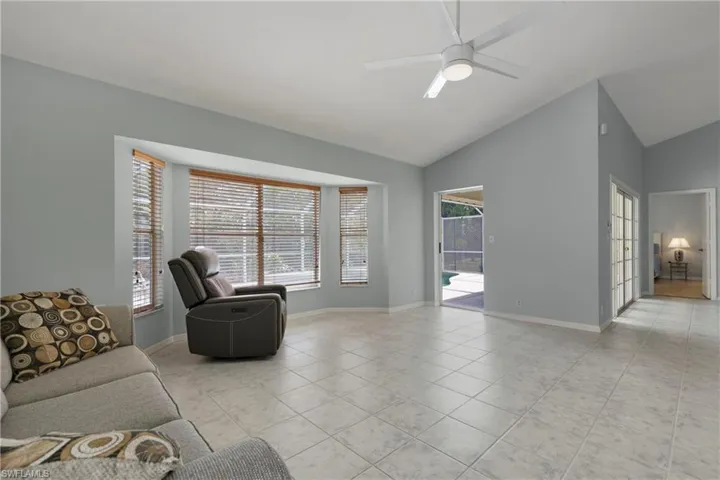 Living room featuring vaulted ceiling, a ceiling fan, light tile patterned flooring, and baseboards