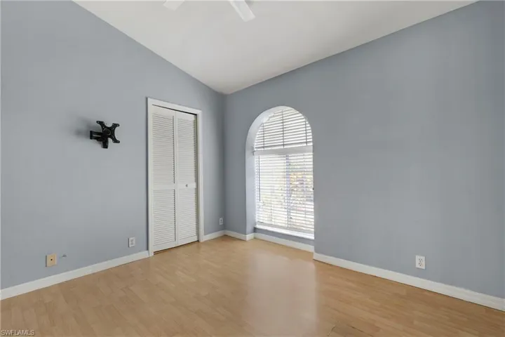 Empty room with vaulted ceiling, light wood-type flooring, a ceiling fan, and baseboards