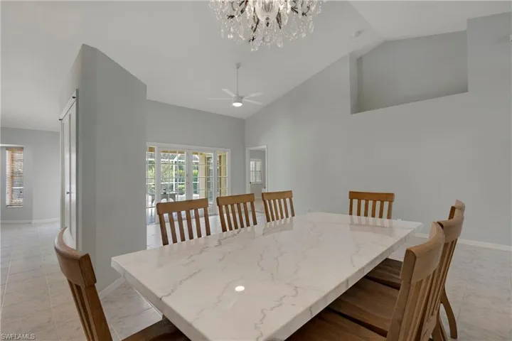 Dining room with a chandelier, a ceiling fan, baseboards, and high vaulted ceiling