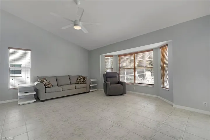 Living area featuring vaulted ceiling, plenty of natural light, a ceiling fan, and baseboards
