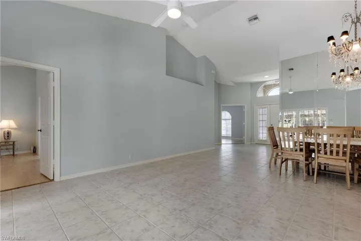 Dining area featuring a chandelier, high vaulted ceiling, light tile patterned flooring, a ceiling fan, and baseboards