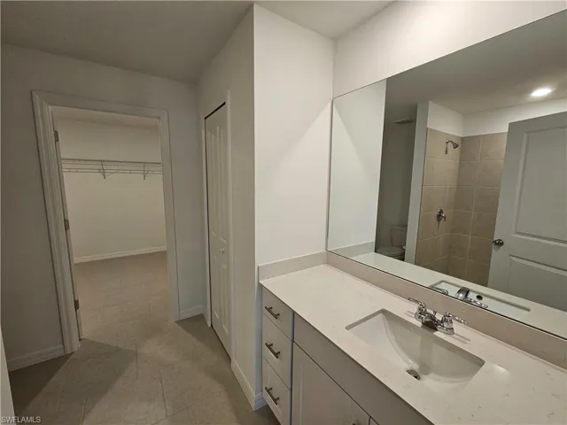 Bathroom vanity with an integrated sink, polished chrome faucet, and expansive wall-mounted mirror