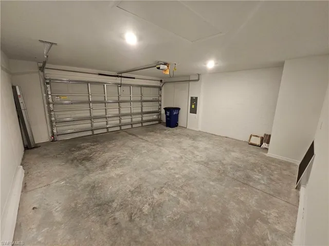 Spacious garage featuring a concrete floor, overhead lighting, and an automatic garage door opener