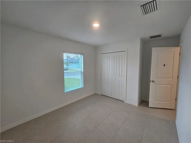 Room featuring tile flooring, white baseboards, a window with blinds, bi-fold closet doors, and recessed lighting