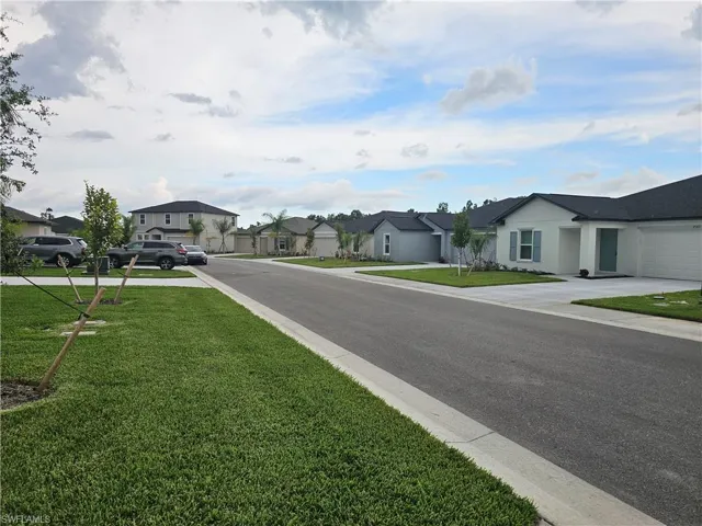 Neighborhood street featuring newly constructed homes with manicured lawns and concrete driveways