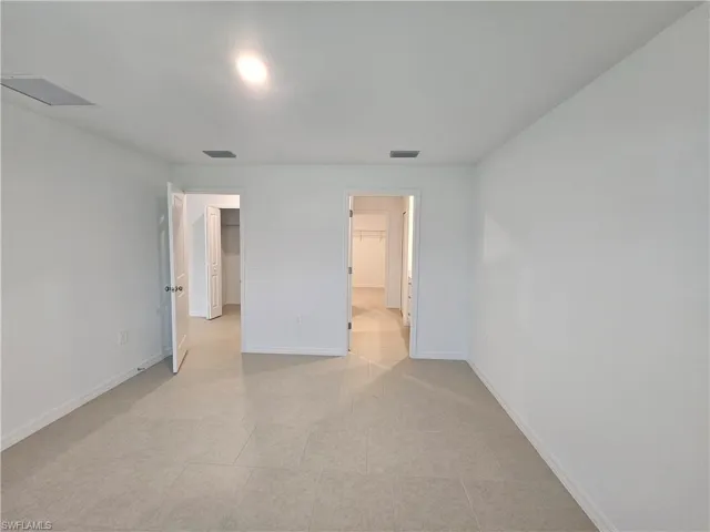 Spacious room featuring light-toned tile flooring, white walls, and recessed lighting