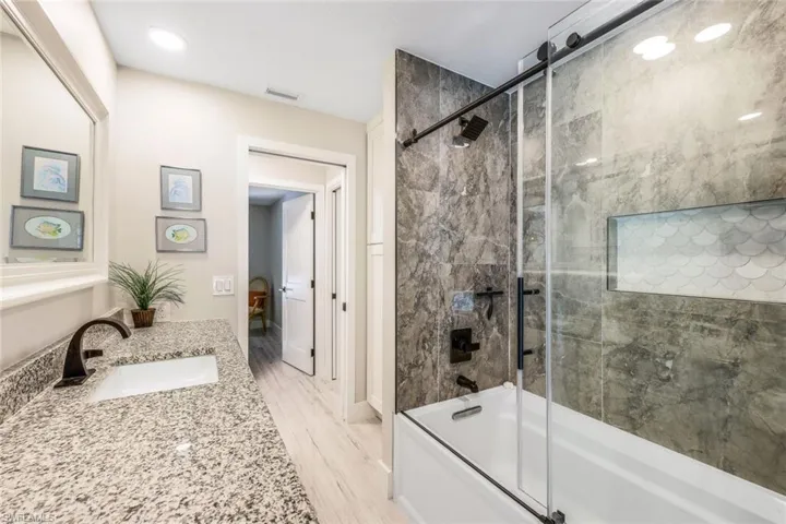 Bathroom featuring shower / bath combination with glass door, hardwood / wood-style floors, and vanity