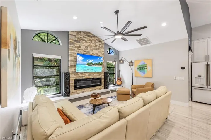 Living room featuring vaulted ceiling, ceiling fan, and a fireplace