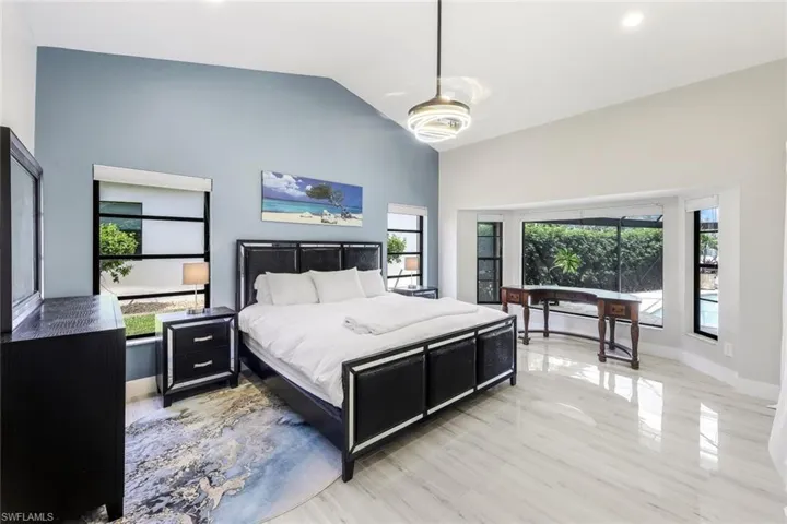 Bedroom featuring ceiling fan, lofted ceiling, light wood-type flooring, and multiple windows
