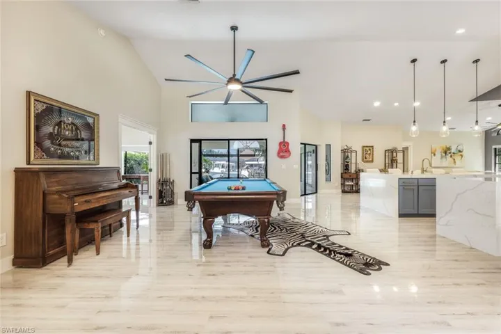 Playroom with ceiling fan, sink, billiards, a towering ceiling, and light hardwood / wood-style floors