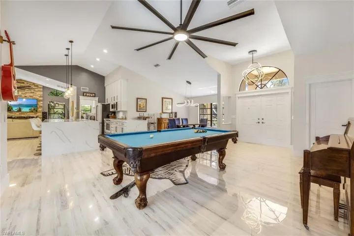 Playroom featuring light hardwood / wood-style flooring, a chandelier, high vaulted ceiling, and billiards