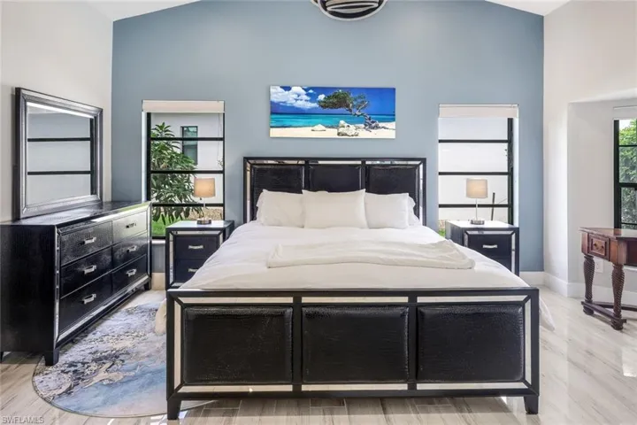 Bedroom with light wood-type flooring and high vaulted ceiling