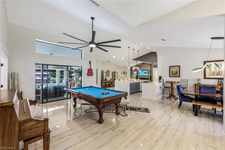 Game room featuring light wood-type flooring, ceiling fan, billiards, and high vaulted ceiling