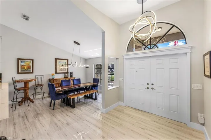 Foyer entrance featuring light hardwood / wood-style floors, lofted ceiling, and a notable chandelier