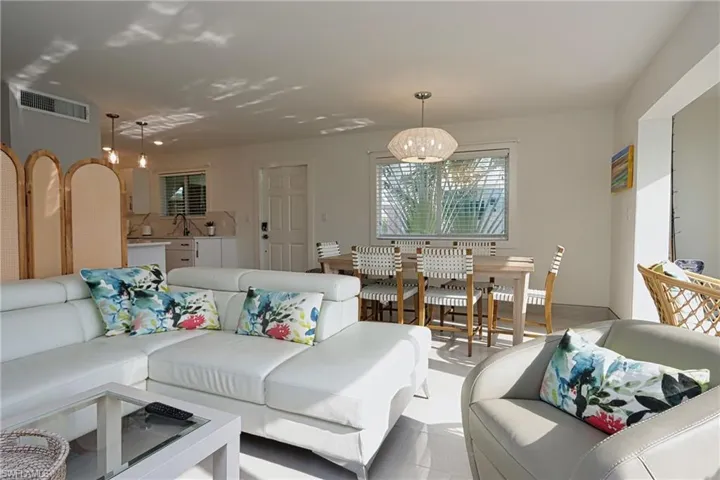 Living room with a notable chandelier, sink, and light tile flooring
