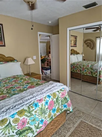 Bedroom featuring neutral wall paint, a built-in ceiling fan, and light-toned tile flooring