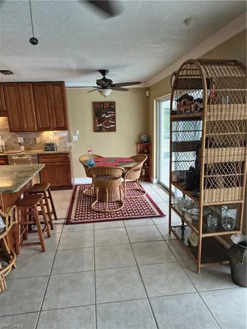 Kitchen and dining area featuring tile flooring, wood cabinetry, stone countertops, a tile backsplash, and a sliding glass door