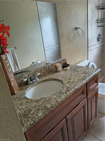 Bathroom vanity featuring a granite-style countertop, undermount sink, and wood-finish cabinetry