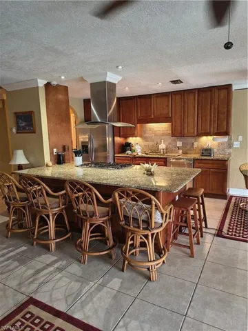 Kitchen featuring a large central island with a stone countertop and integrated breakfast bar
