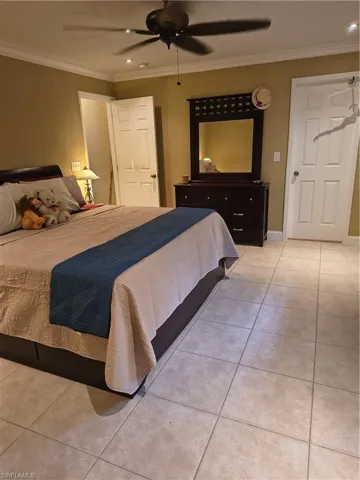 Neutral-toned square tile flooring extends throughout the room, complemented by a ceiling fan with integrated lighting