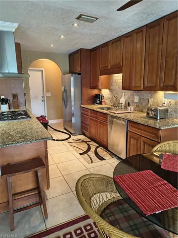 Kitchen featuring wood-finish cabinetry, granite countertops, tile flooring, and stainless steel appliances