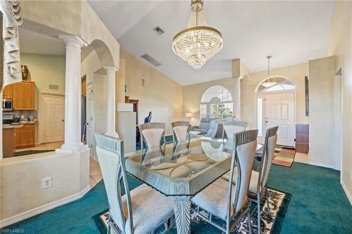 Dining area featuring carpet, ornate columns, suspended lighting, arched walkways, and lofted ceiling