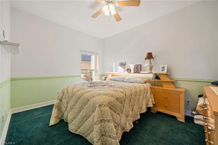Bedroom with dark colored carpet and ceiling fan