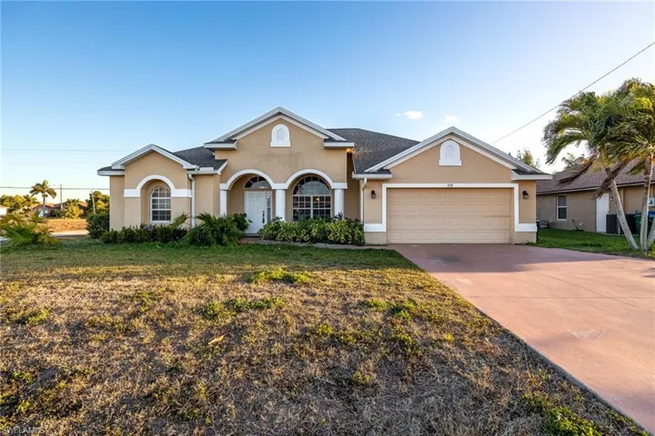 Traditional-style house featuring stucco siding, a garage, concrete driveway, and a front lawn