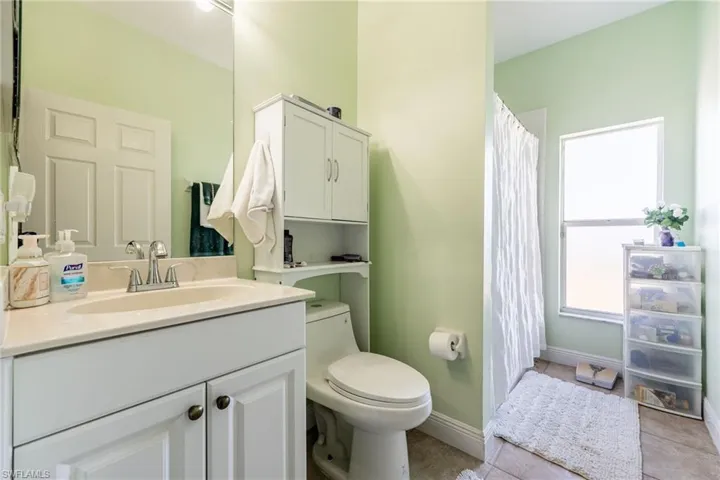 Full bathroom with curtained shower, vanity, and light tile patterned flooring