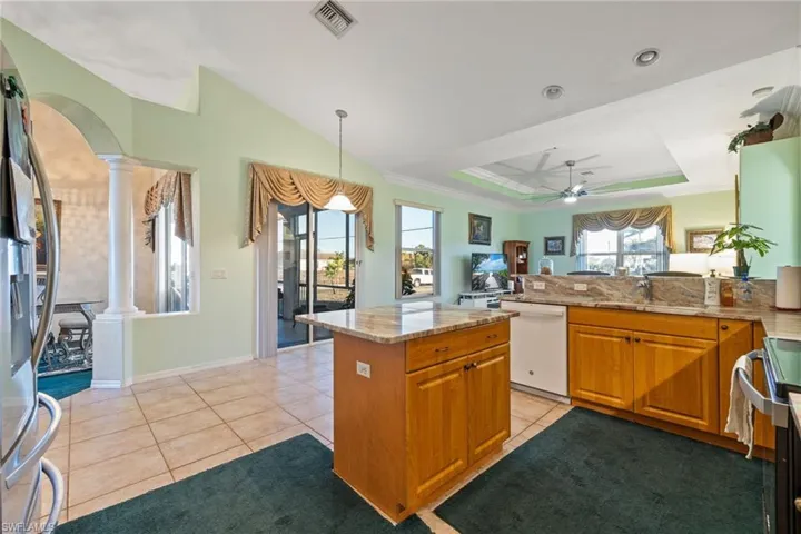 Kitchen with a raised ceiling, stainless steel fridge, arched walkways, wood finish cabinetry, and range